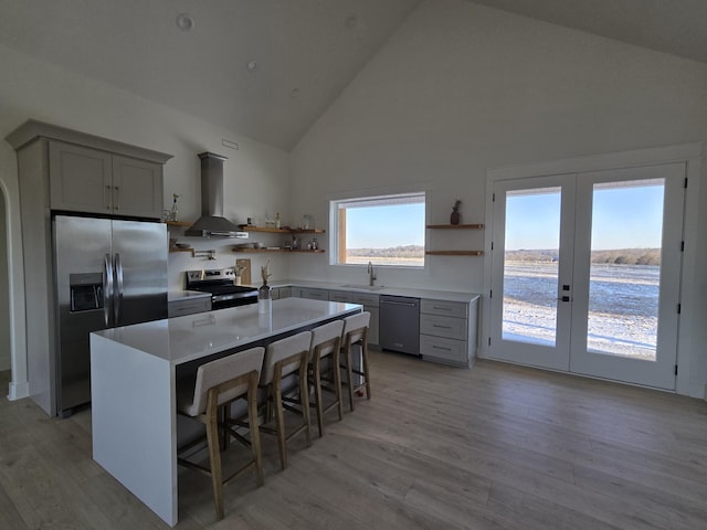 kitchen with a breakfast bar area, light countertops, appliances with stainless steel finishes, a sink, and exhaust hood