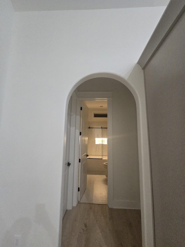 hallway featuring arched walkways and dark wood finished floors