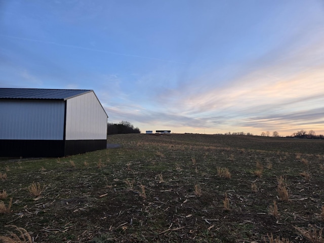 yard at dusk featuring a rural view