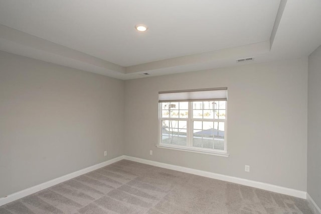 unfurnished room featuring recessed lighting, a raised ceiling, light colored carpet, visible vents, and baseboards