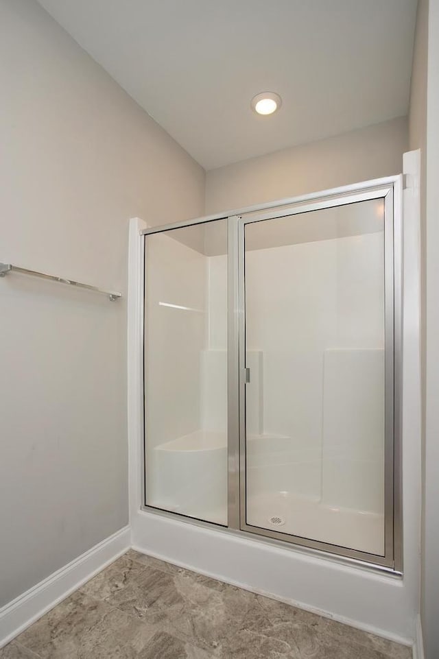 full bathroom with a shower with door and baseboards