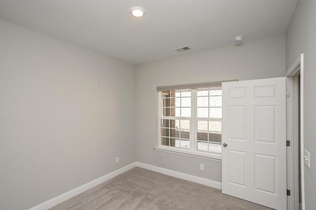 empty room with light carpet, visible vents, and baseboards