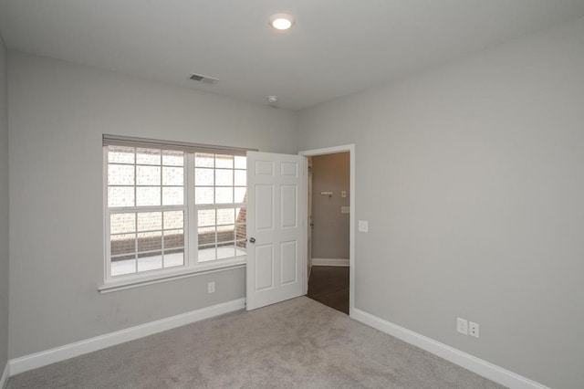 empty room featuring light carpet, baseboards, and visible vents