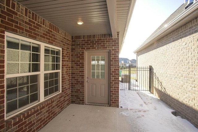 entrance to property featuring a patio area, a gate, fence, and brick siding