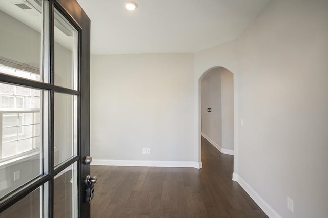 spare room with arched walkways, recessed lighting, dark wood finished floors, and baseboards