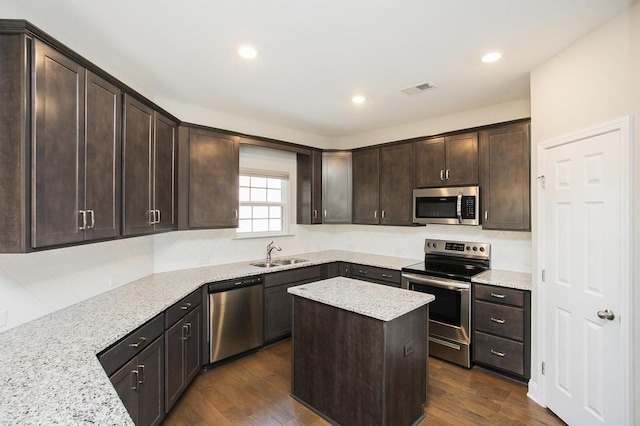 kitchen with visible vents, appliances with stainless steel finishes, light stone counters, a center island, and a sink