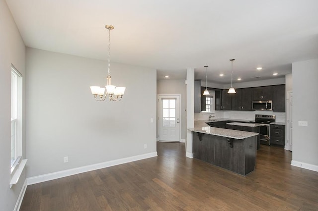 kitchen with a peninsula, dark wood-style floors, appliances with stainless steel finishes, and a breakfast bar area