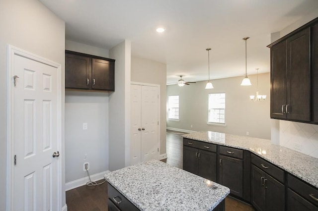 kitchen featuring dark brown cabinetry, light stone countertops, and dark wood finished floors