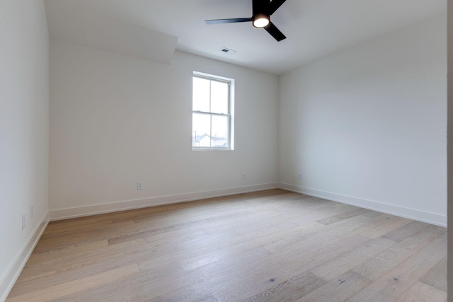 spare room with light wood finished floors, baseboards, visible vents, and a ceiling fan