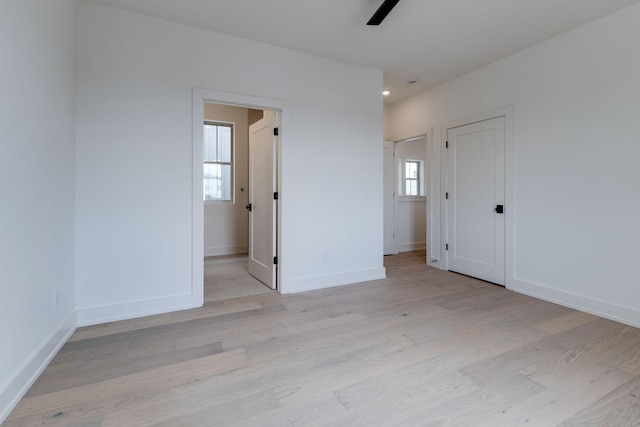 unfurnished bedroom featuring a ceiling fan, baseboards, and light wood finished floors