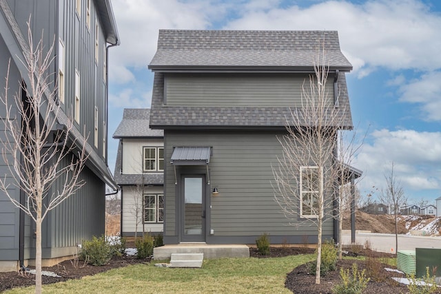 view of front of home with a shingled roof and a front lawn