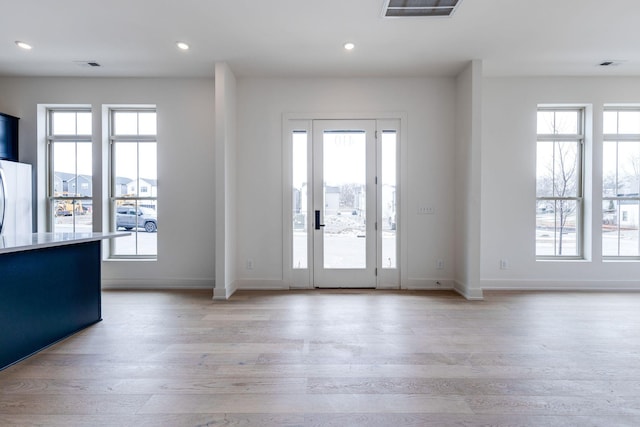 foyer entrance with a wealth of natural light, visible vents, and light wood finished floors