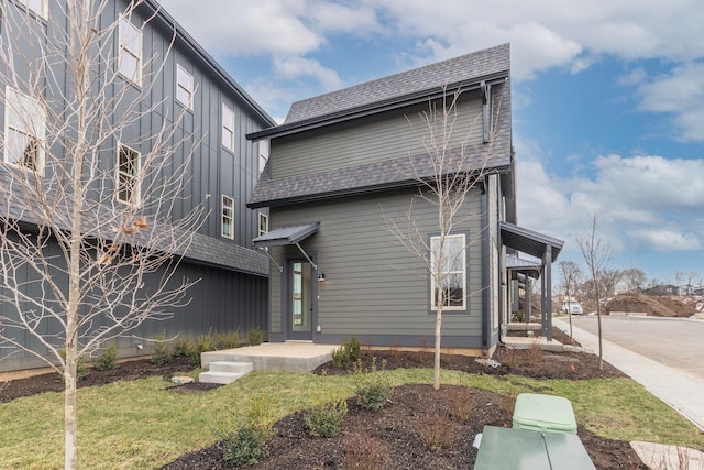 rear view of property featuring a shingled roof and a yard