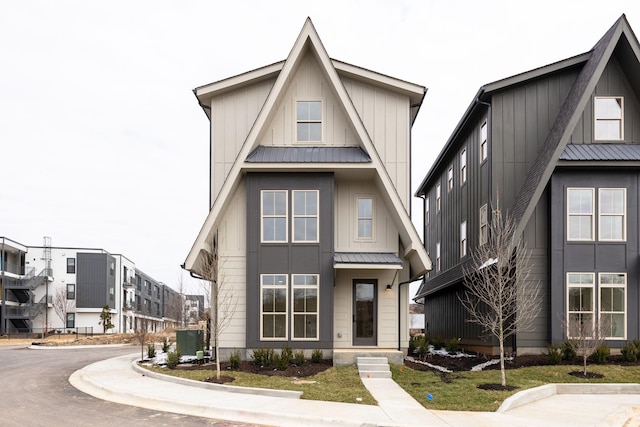 view of front facade with board and batten siding, cooling unit, a standing seam roof, and metal roof