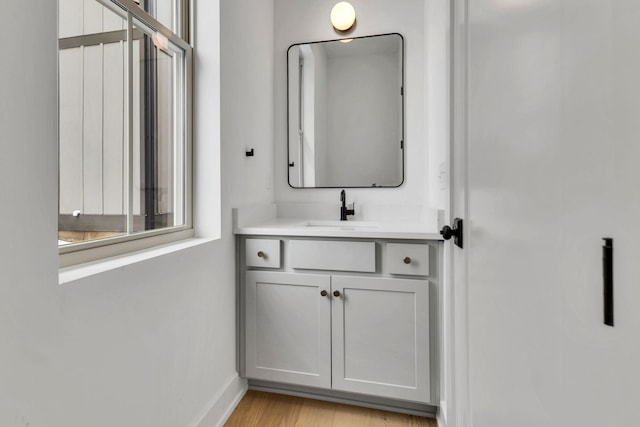 bathroom with wood finished floors, vanity, and baseboards