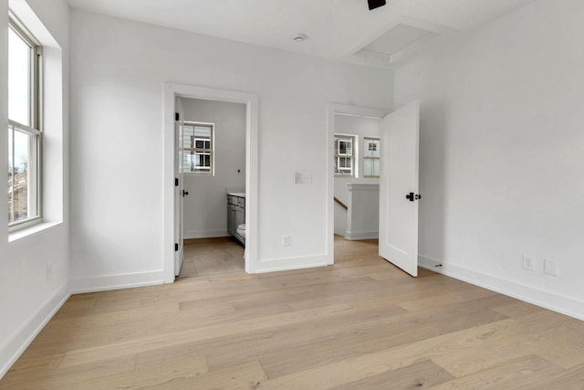 unfurnished bedroom with light wood-type flooring, attic access, and multiple windows