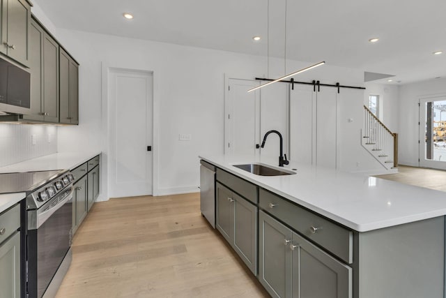 kitchen featuring stainless steel appliances, gray cabinets, light countertops, and a sink