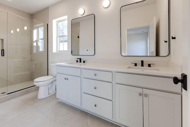 bathroom featuring toilet, a stall shower, double vanity, and a sink