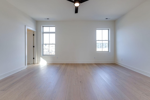 empty room with light wood-style floors, visible vents, baseboards, and ceiling fan