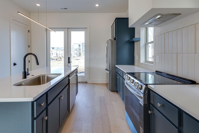 kitchen featuring appliances with stainless steel finishes, light countertops, a sink, and custom exhaust hood