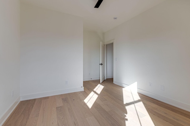 spare room featuring ceiling fan, light wood-style flooring, and baseboards