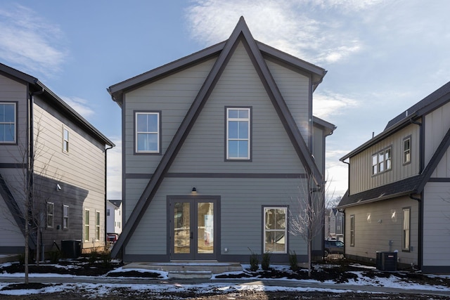 snow covered rear of property featuring central air condition unit and french doors