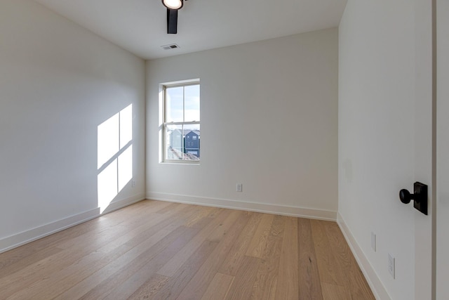 empty room with light wood-type flooring, visible vents, and baseboards