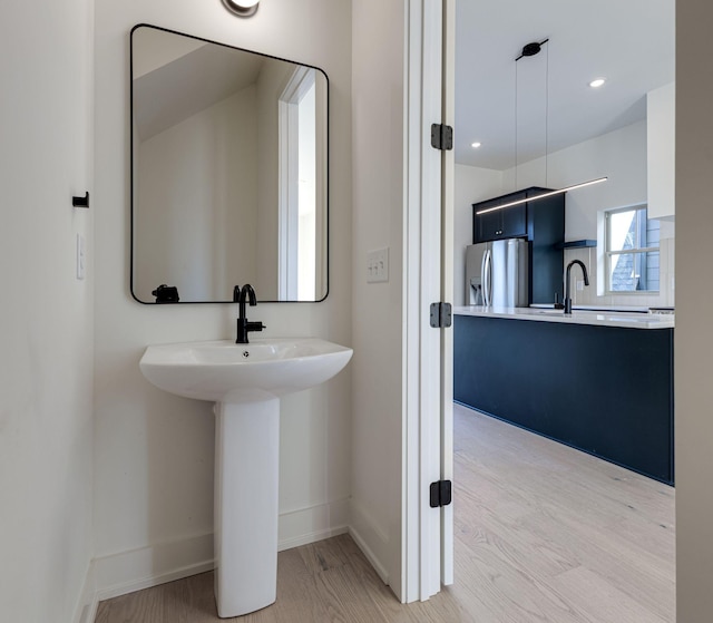 bathroom featuring a sink, baseboards, wood finished floors, and recessed lighting