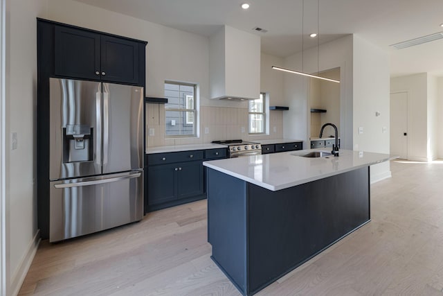 kitchen featuring hanging light fixtures, a kitchen island with sink, stainless steel appliances, light countertops, and a sink