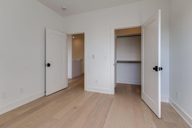 unfurnished bedroom with baseboards, a closet, and light wood-style floors