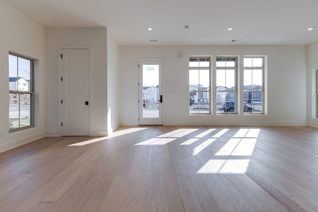 foyer featuring light wood finished floors, a wealth of natural light, and baseboards