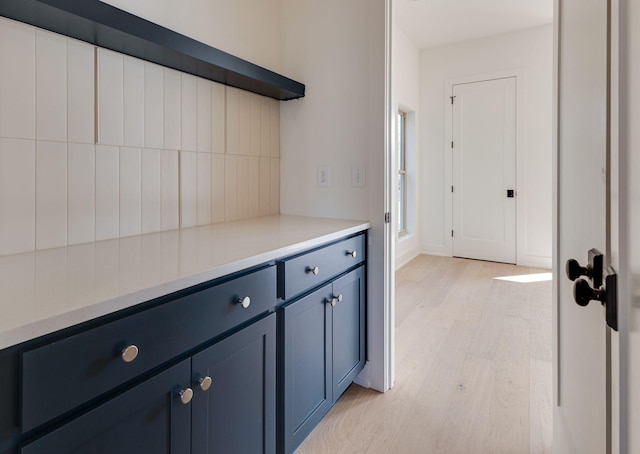 kitchen featuring baseboards, light countertops, light wood-style flooring, and blue cabinets