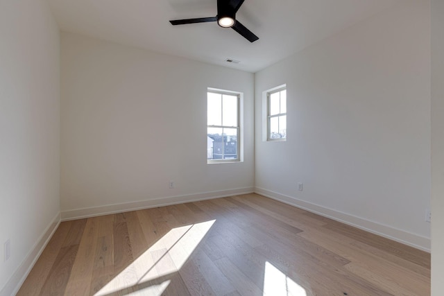 spare room with light wood-type flooring, visible vents, ceiling fan, and baseboards