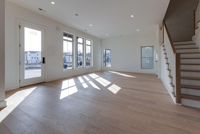 unfurnished living room with stairs, recessed lighting, baseboards, and light wood-style floors