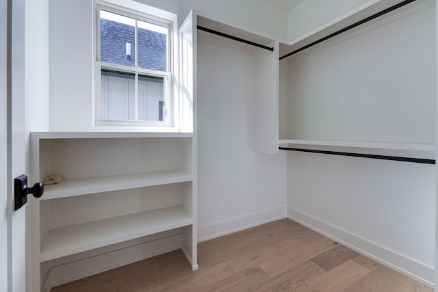 spacious closet with light wood-type flooring and a barn door