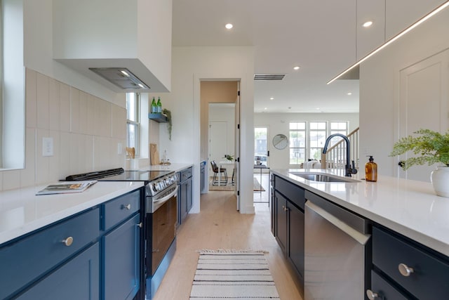 406 Morningside Mnr, Nashville, TN 37209 - kitchen with stainless steel appliances, blue cabinetry, a sink, light wood-style flooring, and backsplash