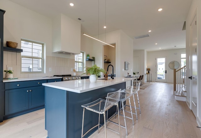406 Morningside Mnr, Nashville, TN 37209 - kitchen with open shelves, stove, light wood finished floors, a kitchen island with sink, and blue cabinetry