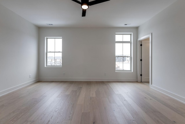 empty room featuring baseboards, a healthy amount of sunlight, visible vents, and light wood finished floors