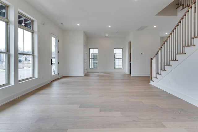 foyer featuring plenty of natural light, light wood-type flooring, and stairs