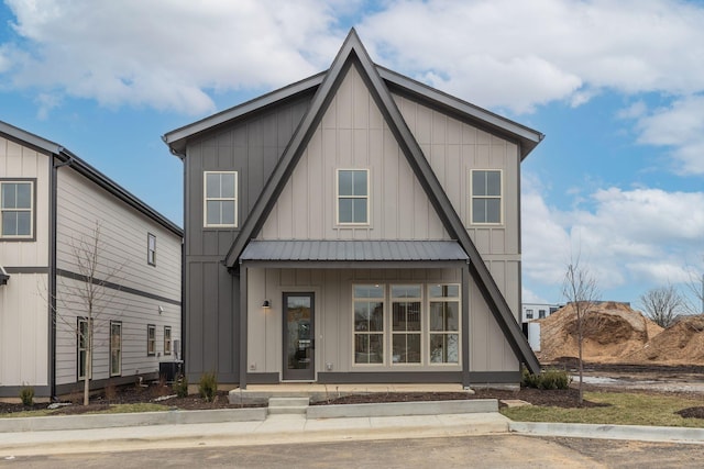 view of front facade with board and batten siding, metal roof, and a porch