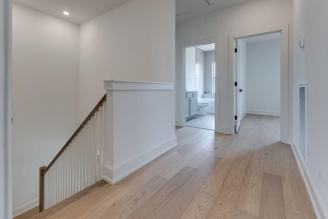 hallway with attic access, baseboards, light wood-style flooring, an upstairs landing, and recessed lighting