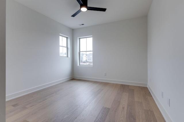 unfurnished room featuring light wood-style flooring, a ceiling fan, visible vents, and baseboards