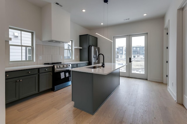 kitchen with a sink, light countertops, appliances with stainless steel finishes, french doors, and pendant lighting