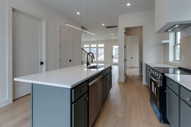 kitchen featuring electric range, a sink, light countertops, stainless steel dishwasher, and an island with sink