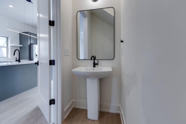 bathroom featuring baseboards, a sink, and wood finished floors