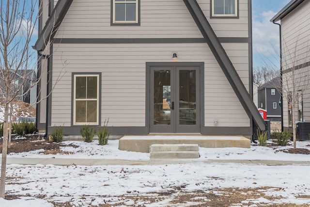 snow covered property entrance featuring french doors