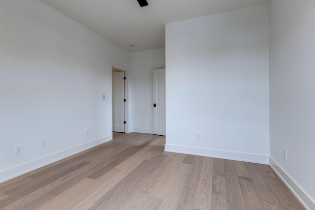 empty room featuring a ceiling fan, light wood-style flooring, and baseboards