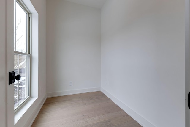 empty room featuring light wood-type flooring, a wealth of natural light, and baseboards