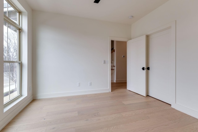 unfurnished room with light wood-style floors, plenty of natural light, and baseboards