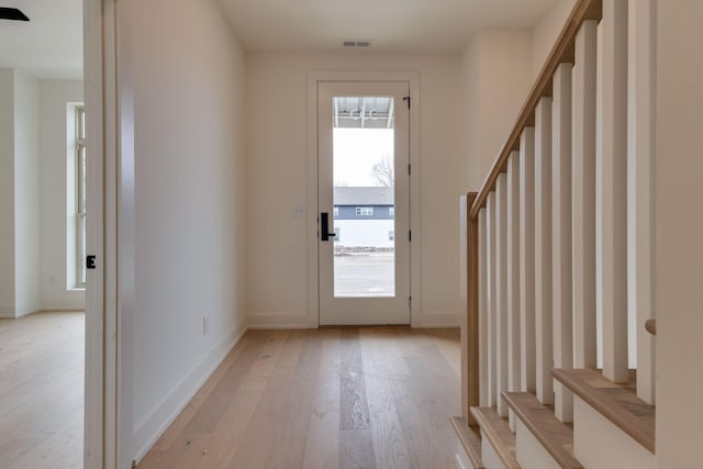 doorway featuring stairs, baseboards, visible vents, and light wood-style floors